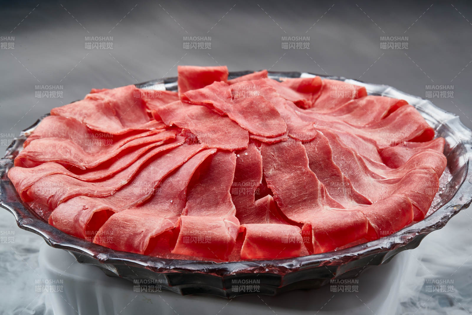干冰缭绕的背景上摆放的鲜牛肉刺身图片