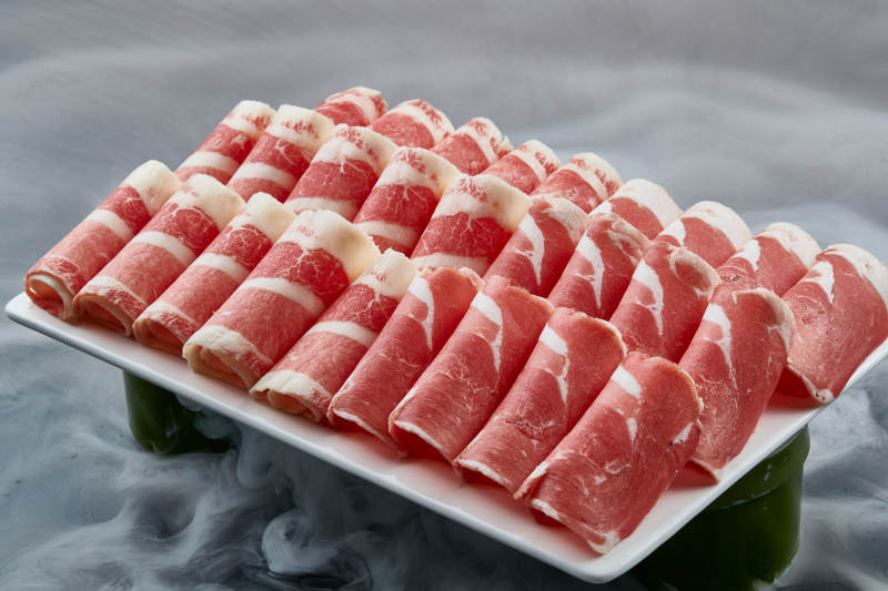 干冰缭绕的背景上摆放的牛羊肉卷双拼图片