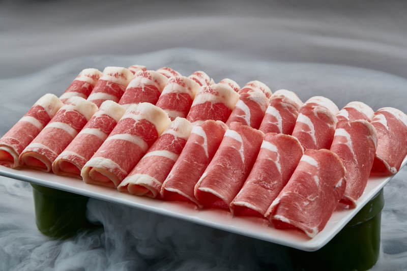 干冰缭绕的背景上摆放的牛羊肉卷双拼图片