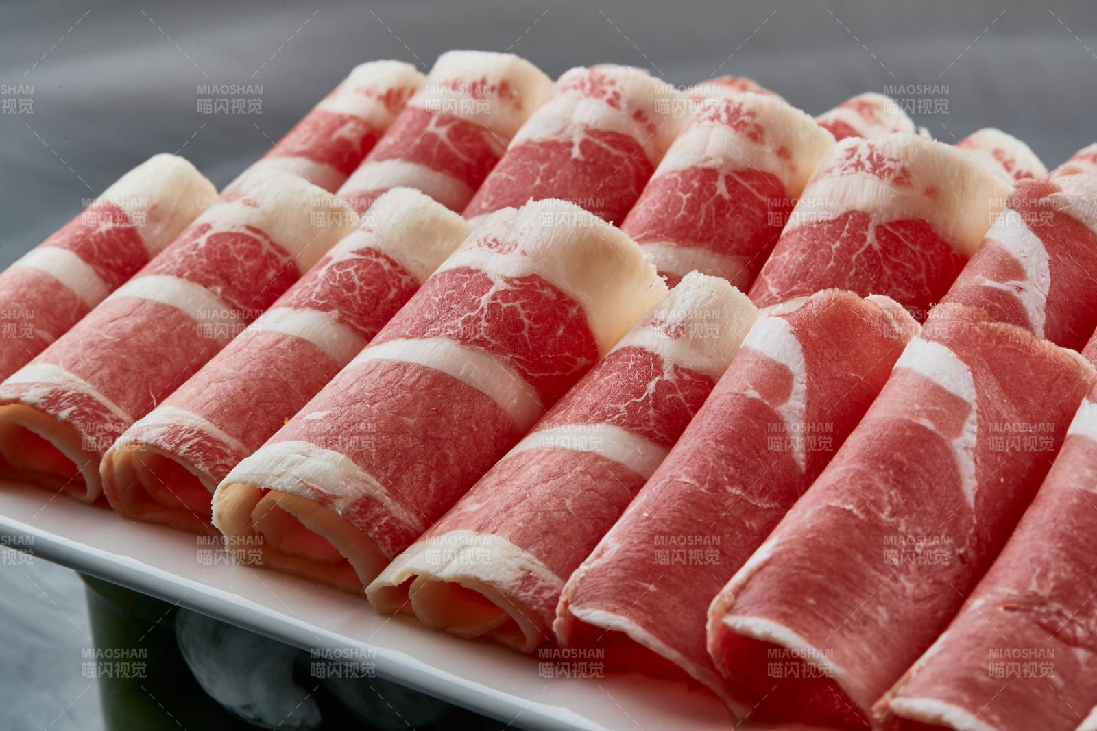 干冰缭绕的背景上摆放的牛羊肉卷双拼图片