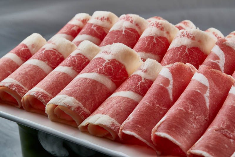 干冰缭绕的背景上摆放的牛羊肉卷双拼图片