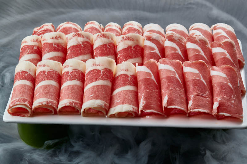 干冰缭绕的背景上摆放的牛羊肉卷双拼图片