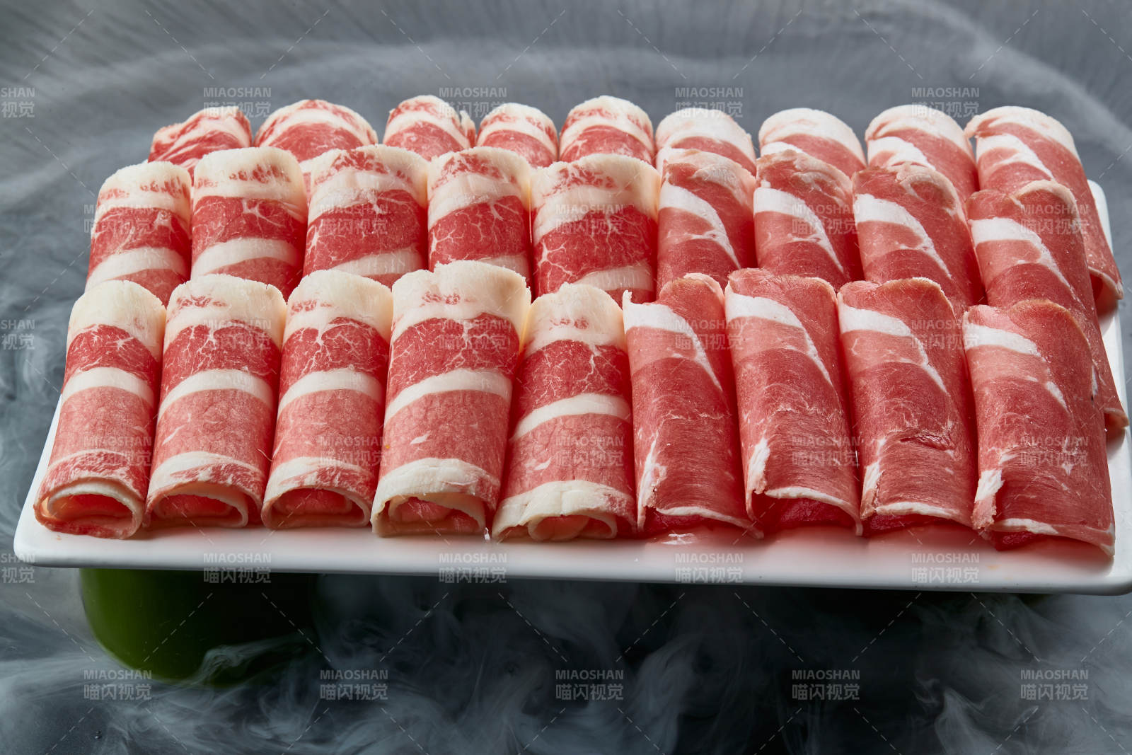 干冰缭绕的背景上摆放的牛羊肉卷双拼图片