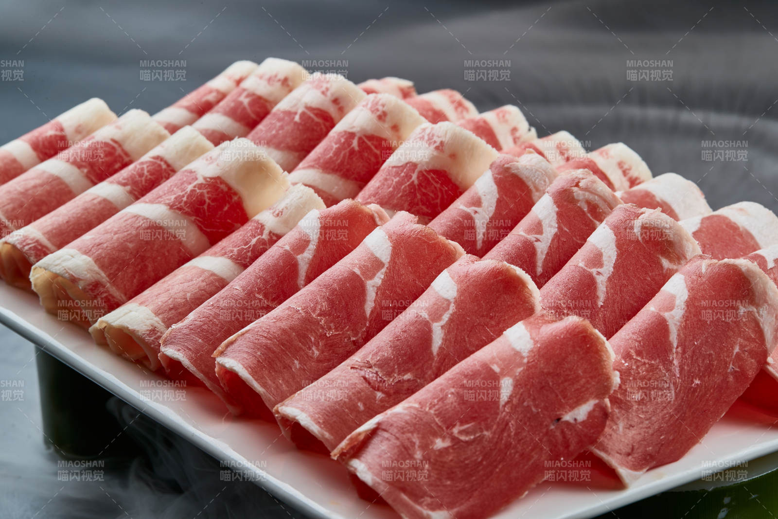 干冰缭绕的背景上摆放的牛羊肉卷双拼图片