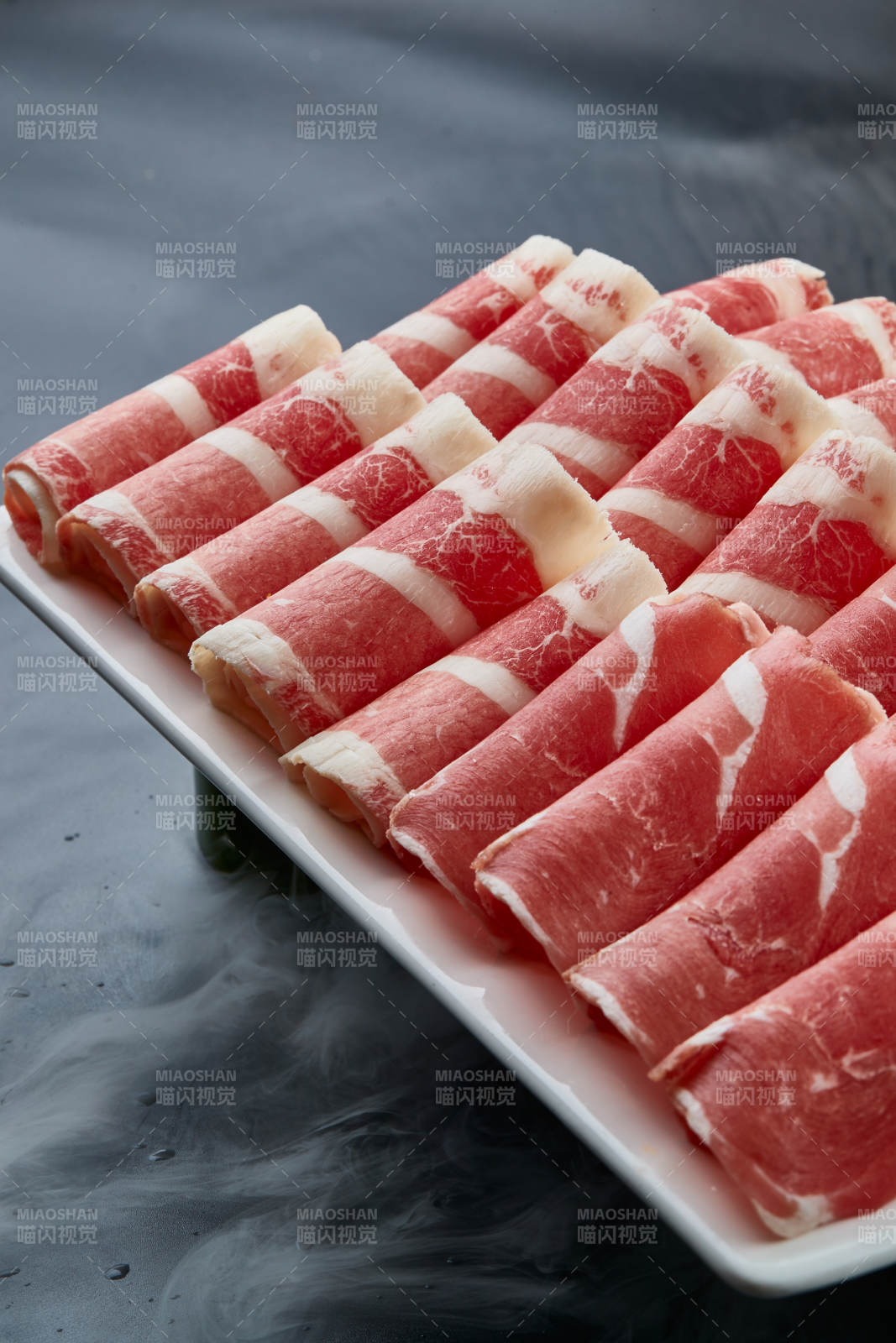 干冰缭绕的背景上摆放的牛羊肉卷双拼图片