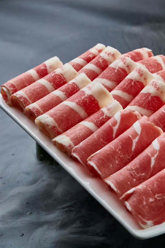 干冰缭绕的背景上摆放的牛羊肉卷双拼图片