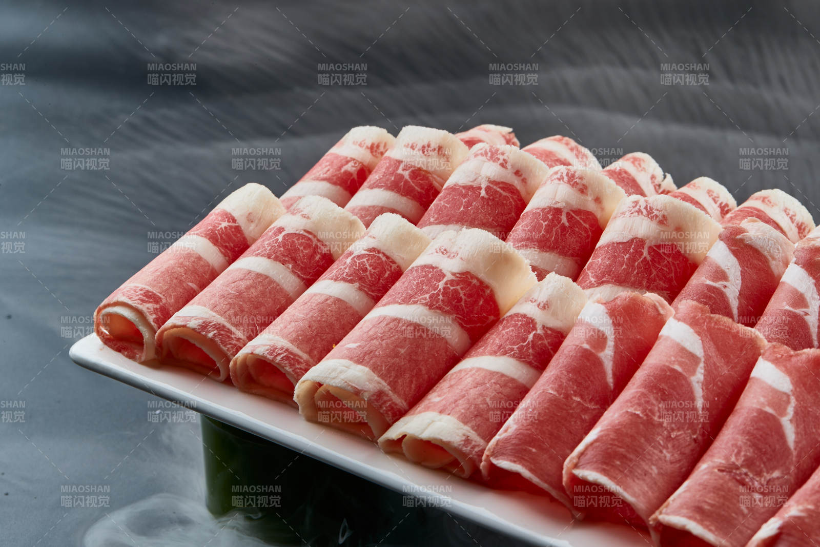 干冰缭绕的背景上摆放的牛羊肉卷双拼图片