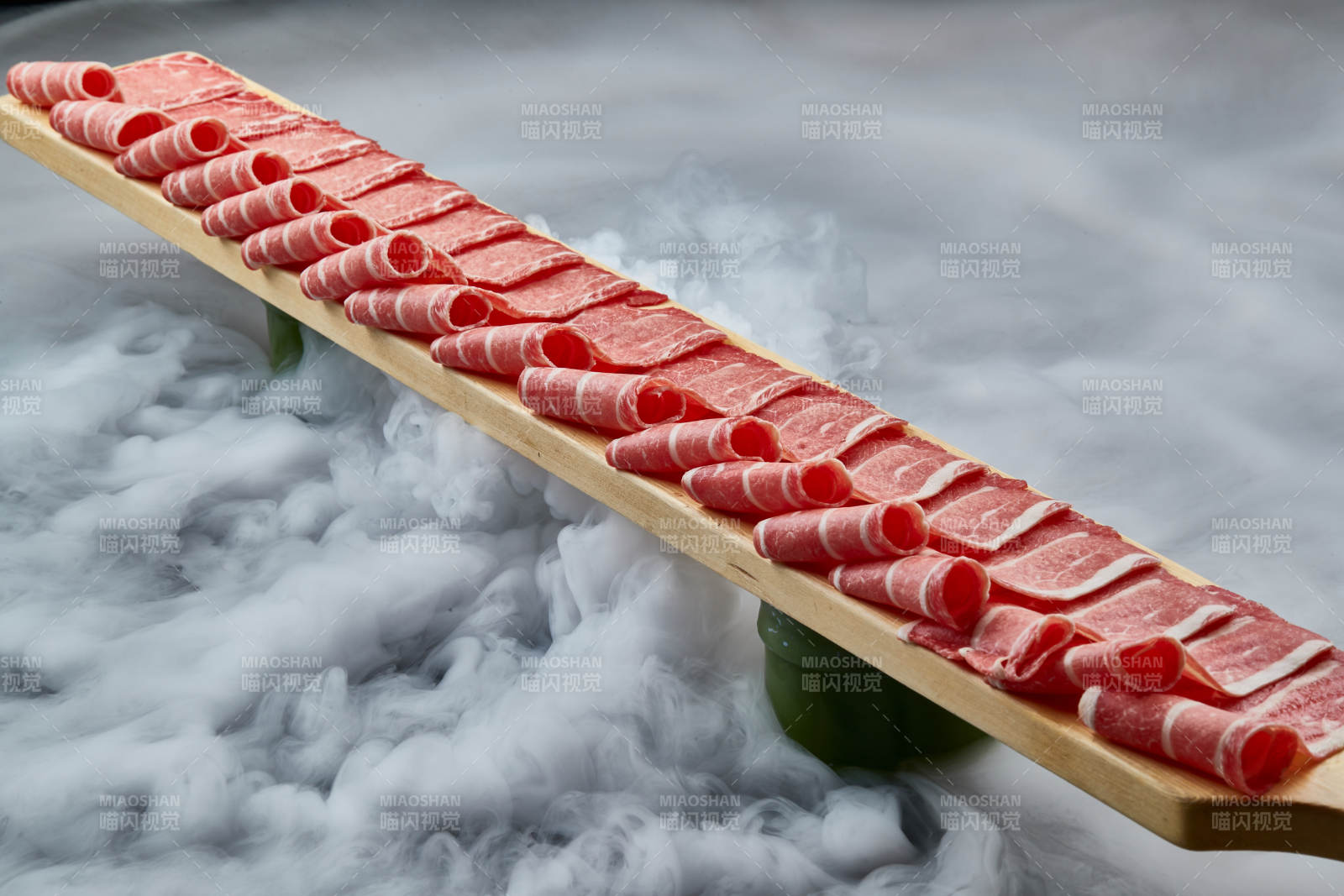 干冰缭绕的背景上摆放的和牛一米肉片图片