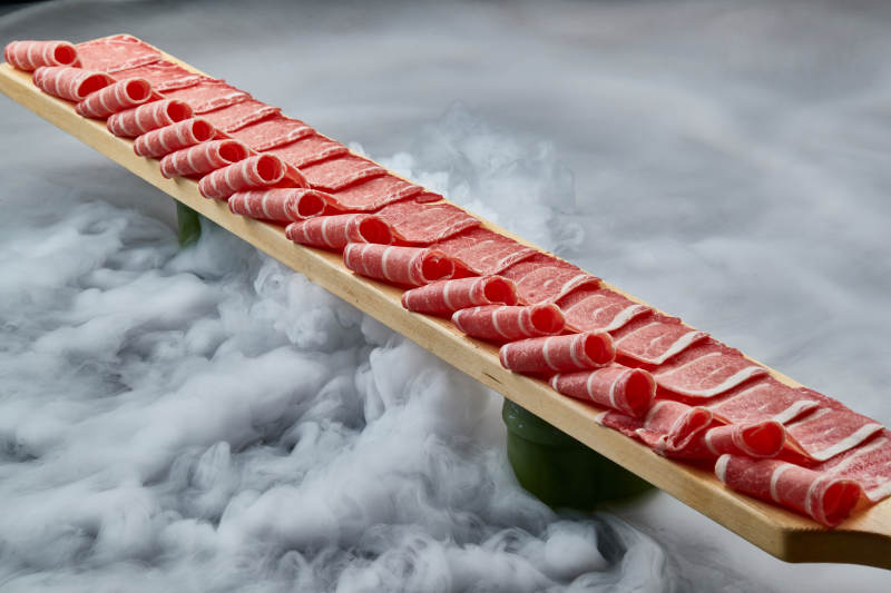 干冰缭绕的背景上摆放的和牛一米肉片图片