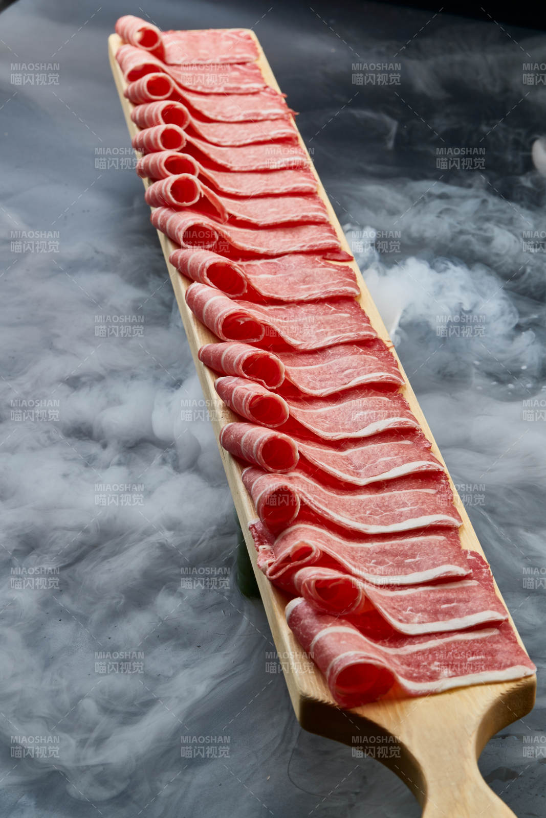 干冰缭绕的背景上摆放的和牛一米肉片图片