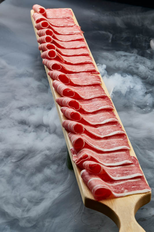 干冰缭绕的背景上摆放的和牛一米肉片图片