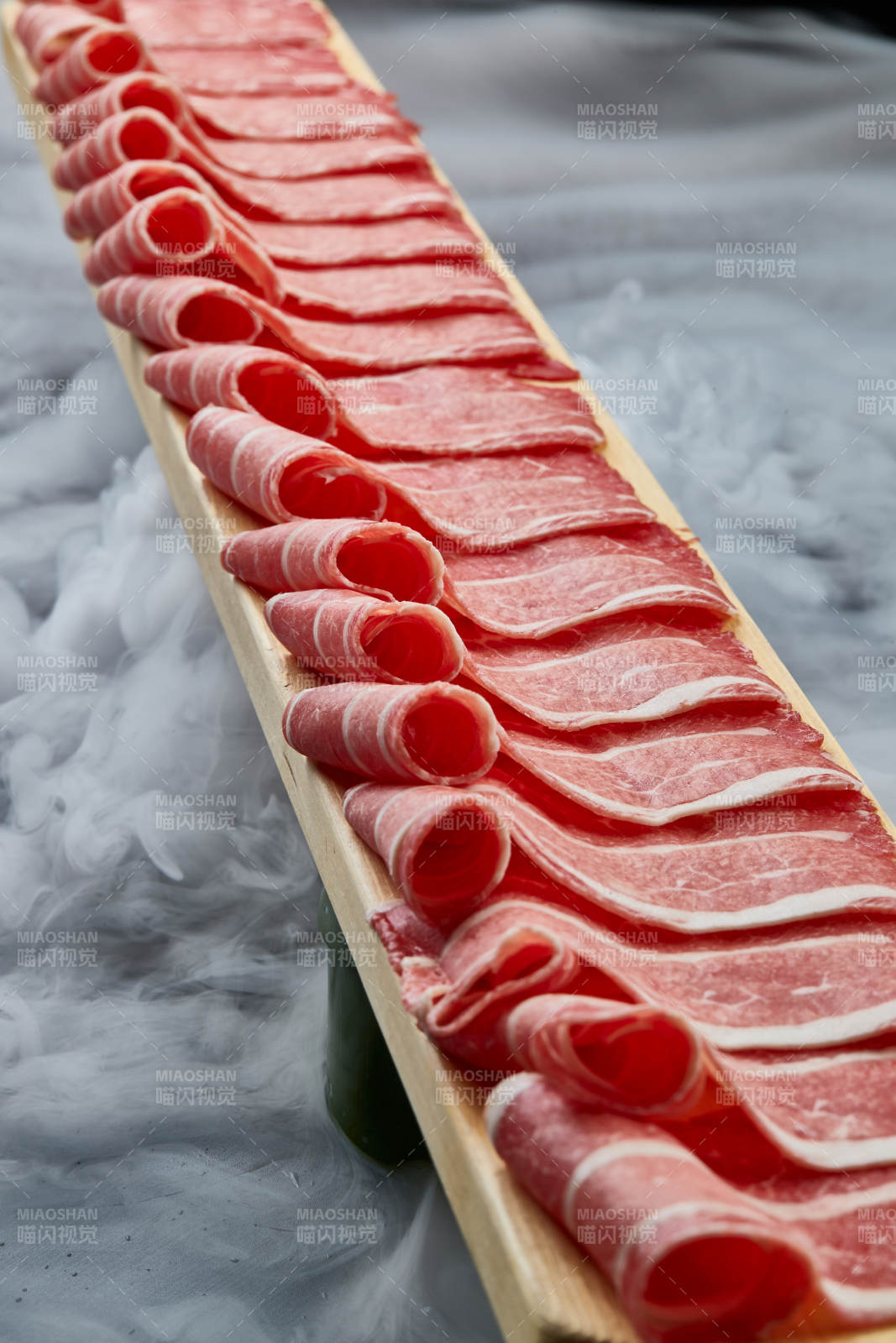 干冰缭绕的背景上摆放的和牛一米肉片图片