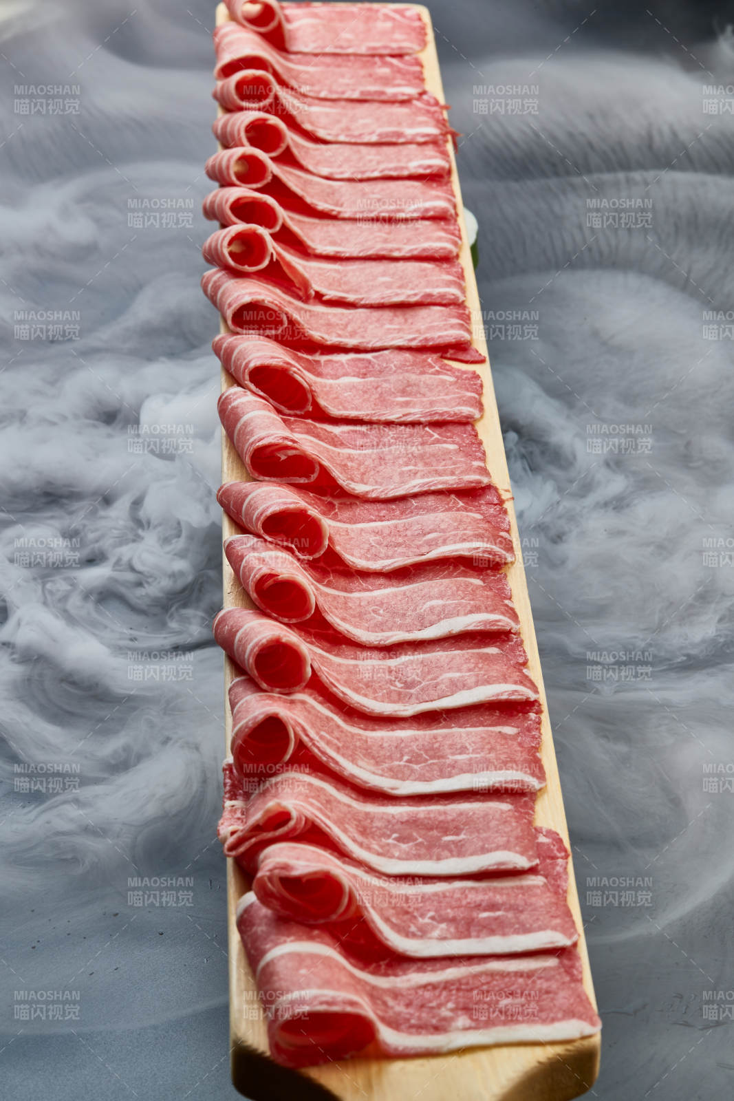 干冰缭绕的背景上摆放的和牛一米肉片图片