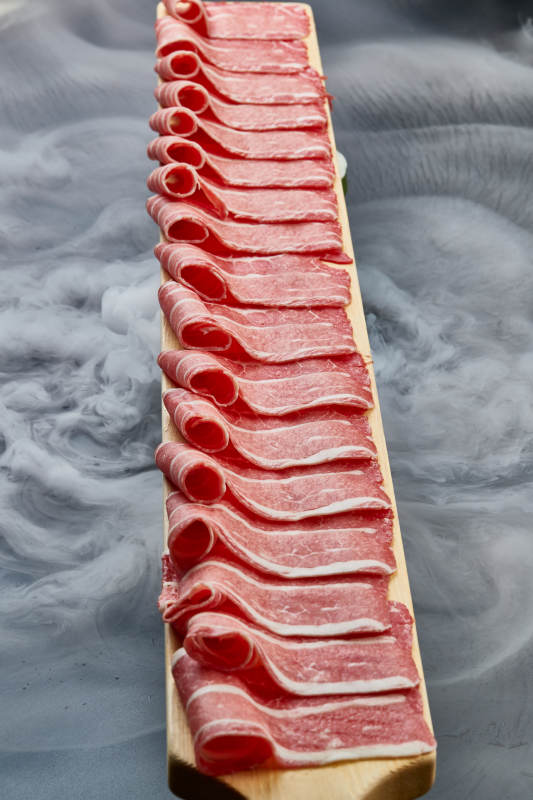 干冰缭绕的背景上摆放的和牛一米肉片图片