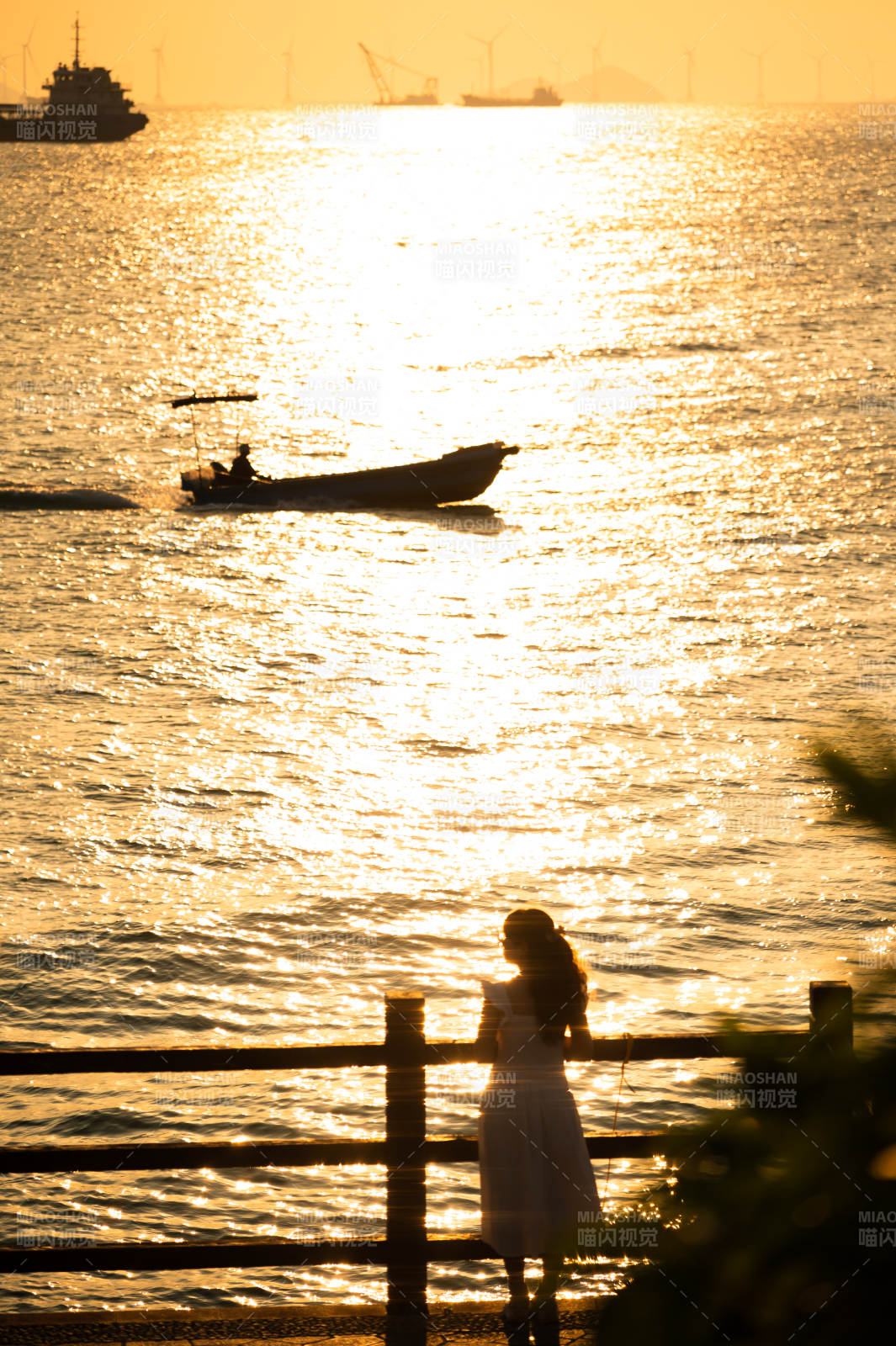 夕阳下的海景与人影。图片
