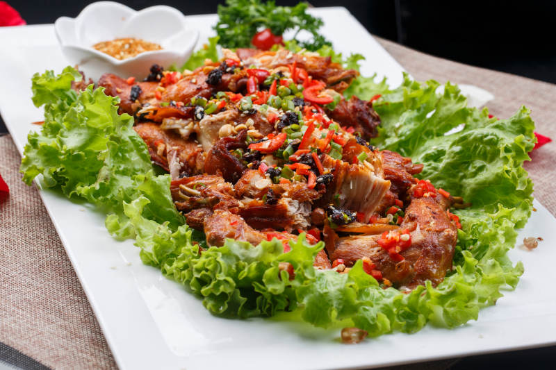 陈旧木板上的方瓷盘装的风味手撕兔图片