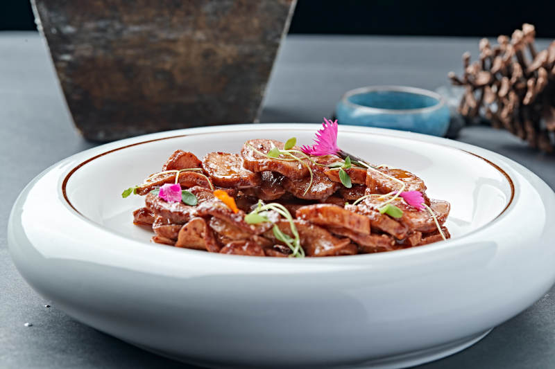 白色瓷盘装的糖腌杏鲍菇片图片