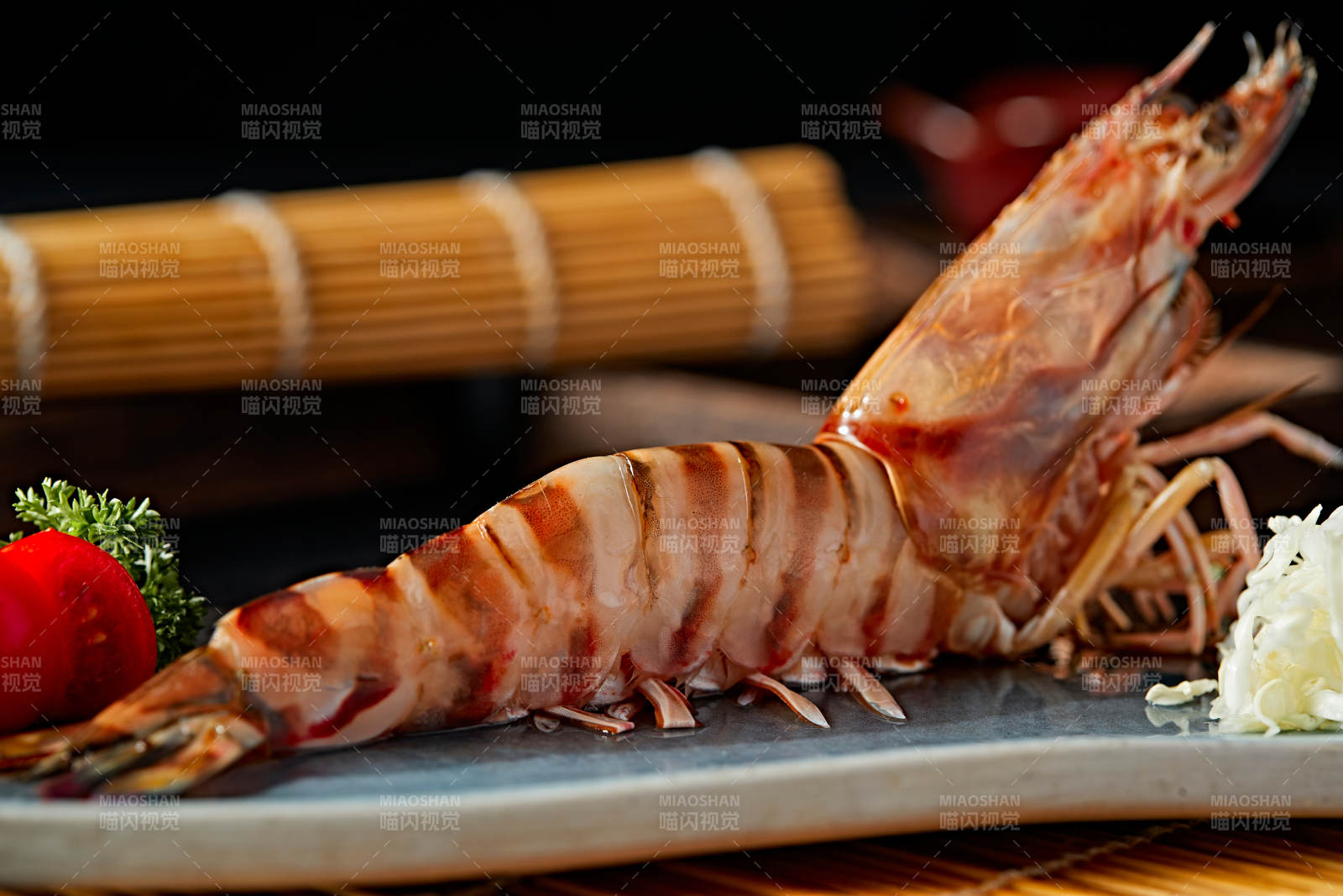 长方形瓷盘装的铁板野生明虾皇摆放在草垫上图片