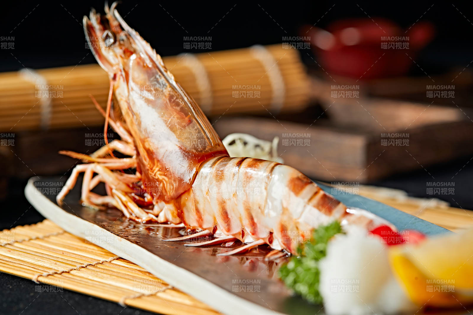 长方形瓷盘装的铁板野生明虾皇摆放在草垫上图片