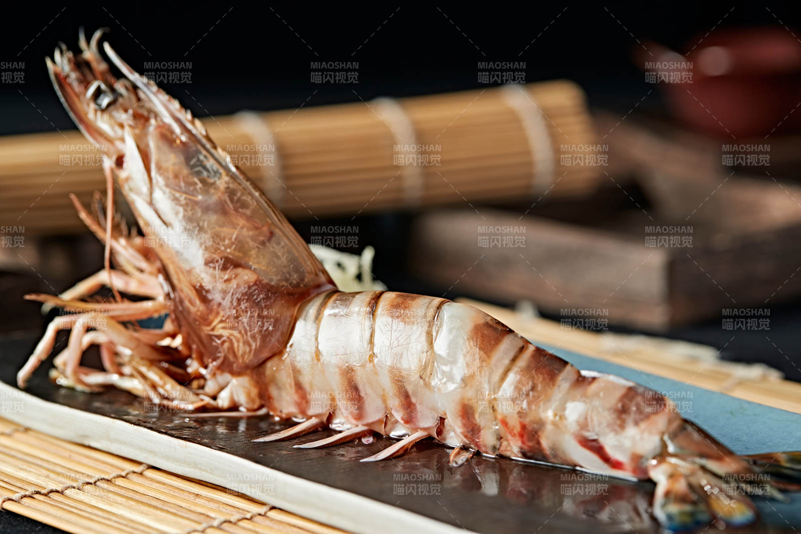 长方形瓷盘装的铁板野生明虾皇摆放在草垫上图片