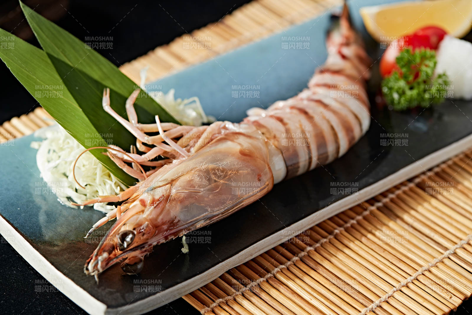 长方形瓷盘装的铁板野生明虾皇摆放在草垫上图片