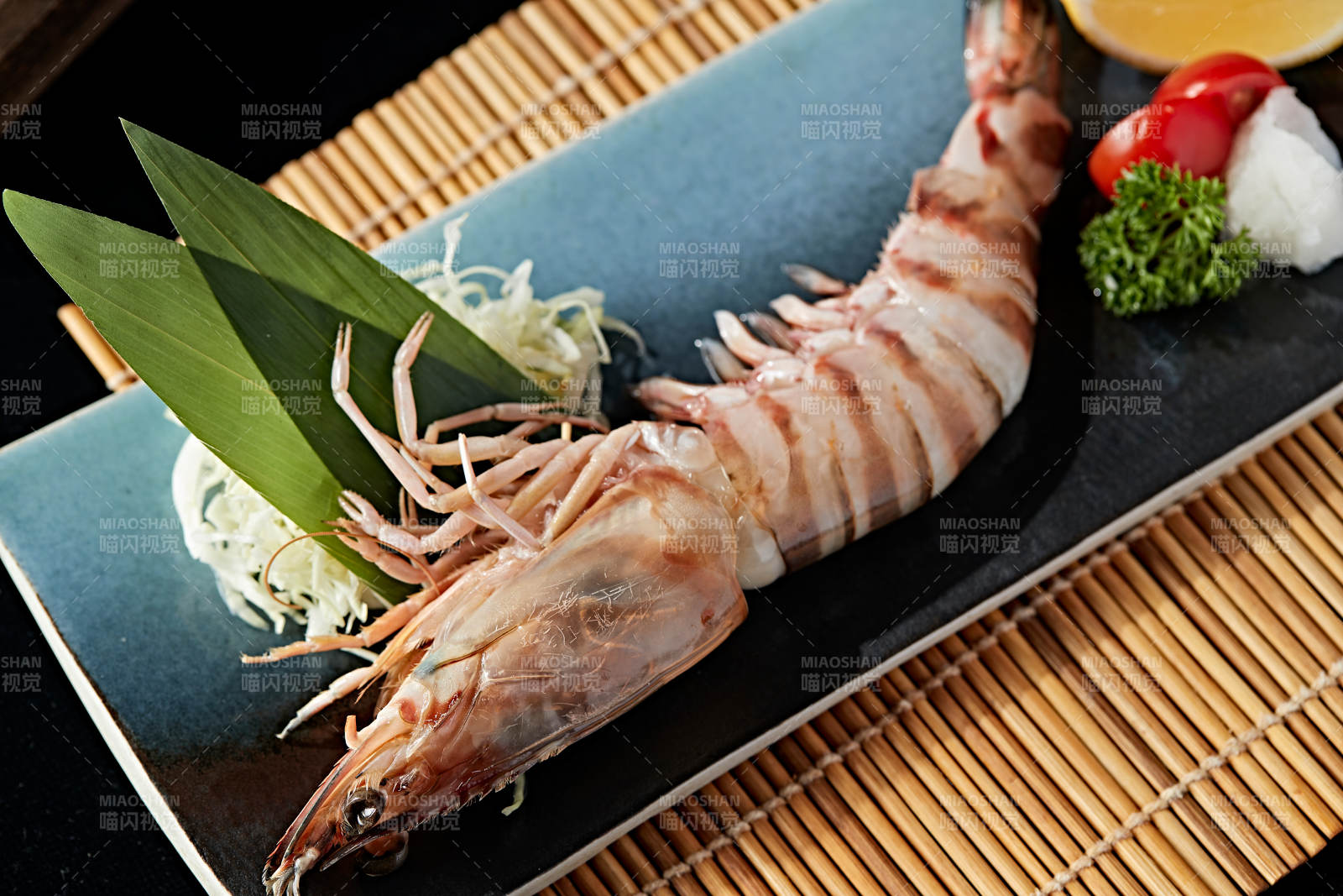 长方形瓷盘装的铁板野生明虾皇摆放在草垫上图片