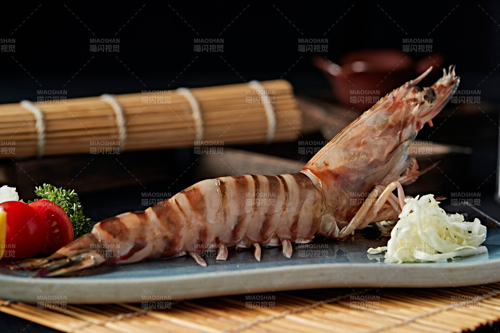 长方形瓷盘装的铁板野生明虾皇摆放在草垫上图片