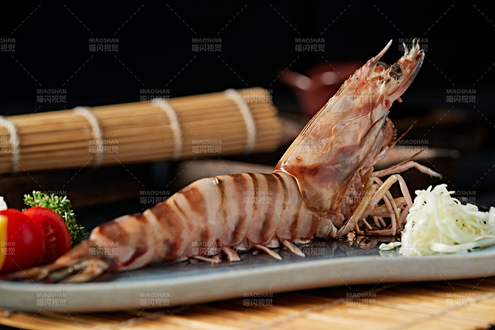 长方形瓷盘装的铁板野生明虾皇摆放在草垫上图片