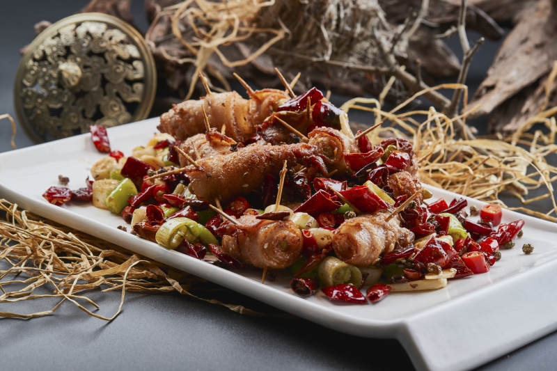 白瓷盘装的辣子油炸五花肉山椒卷图片