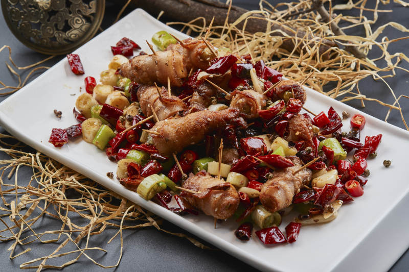 白瓷盘装的辣子油炸五花肉山椒卷图片