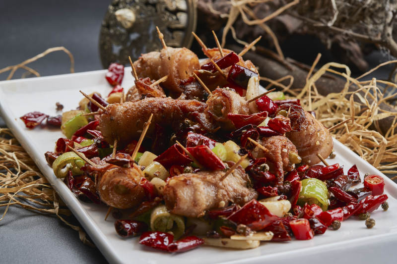 白瓷盘装的辣子油炸五花肉山椒卷图片