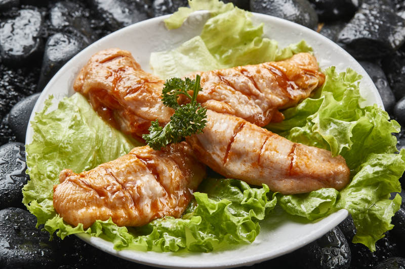 白色瓷盘装的烤肉食材生腌渍鸡翅图片