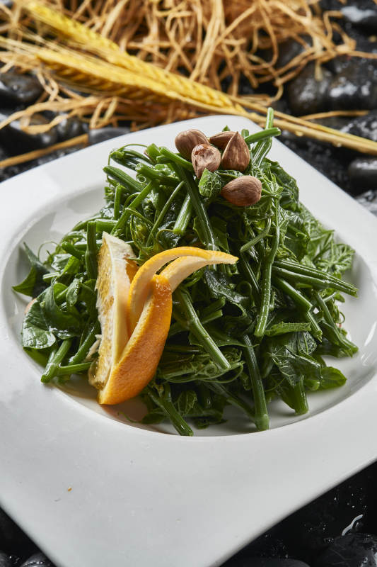 白色瓷盘装的鲜橙杏仁儿拌蕨菜图片