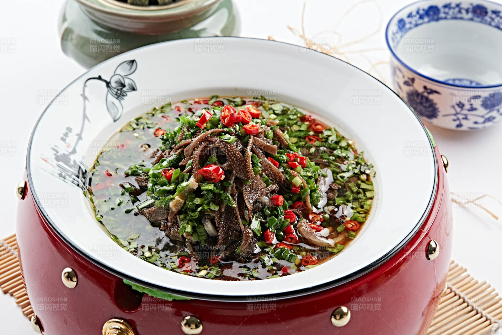 红木底托上的白瓷盘装的葱香毛肚图片