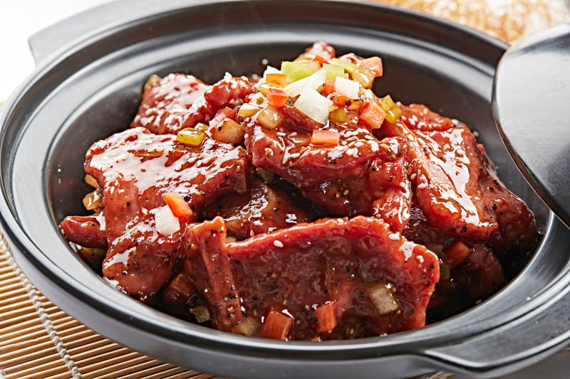 黑色砂锅装的黑胡椒烧牛仔骨图片