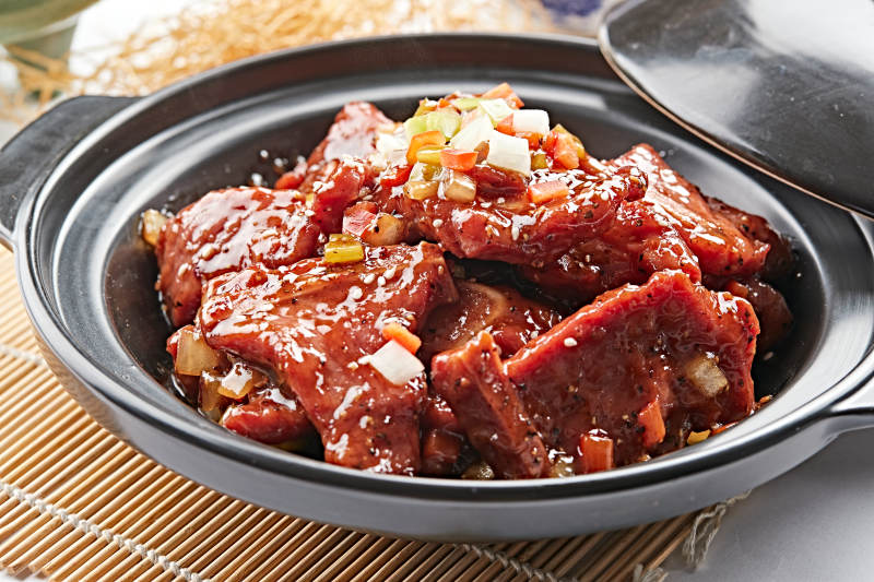 黑色砂锅装的黑胡椒烧牛仔骨图片