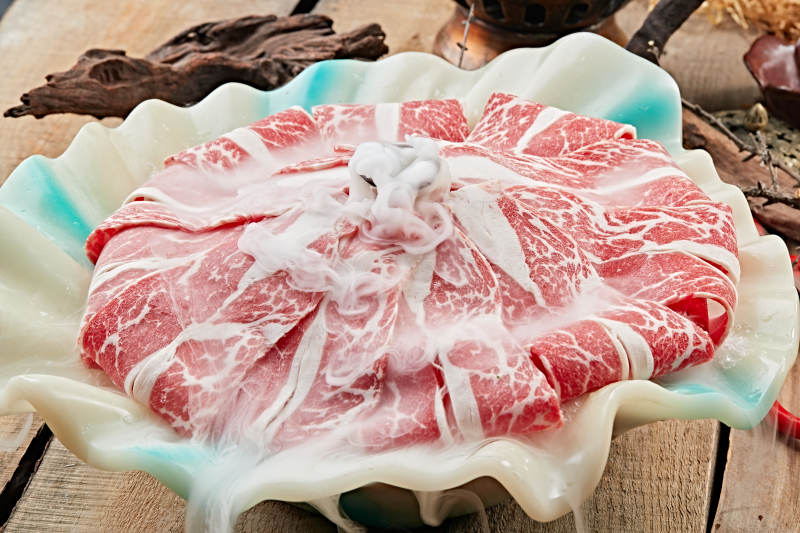 干冰缭绕的背景上摆放的高级雪花肥牛切片图片