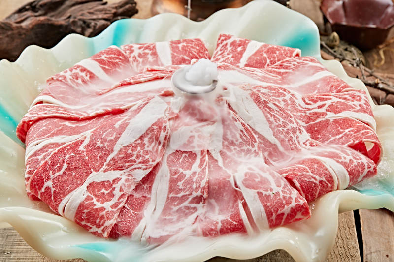 干冰缭绕的背景上摆放的高级雪花肥牛切片图片