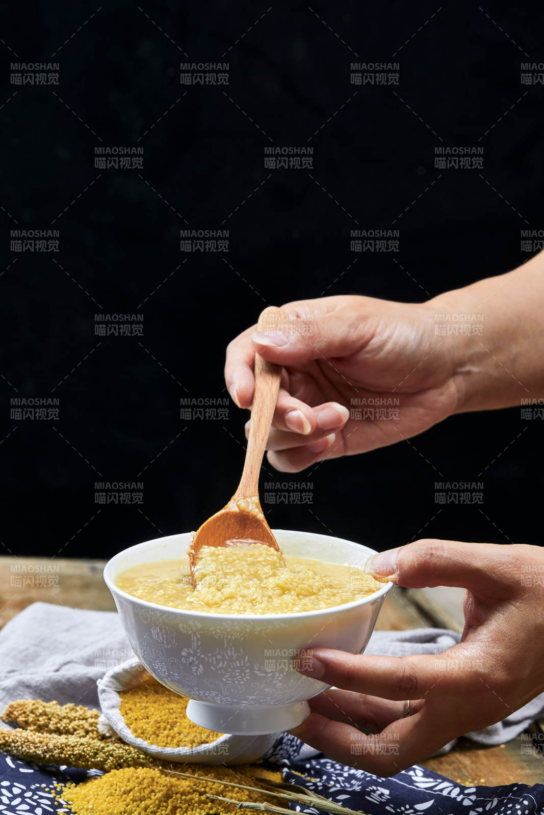 手持木勺㧟起的美味香浓小米粥图片