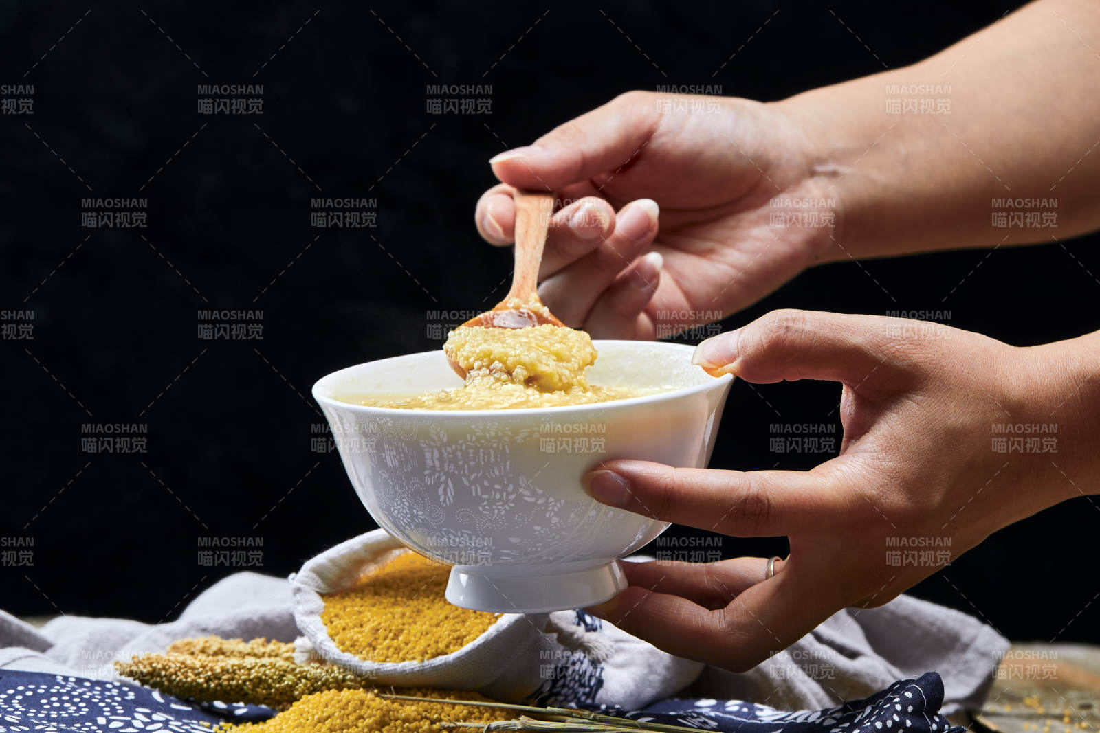 手持木勺㧟起的美味香浓小米粥图片