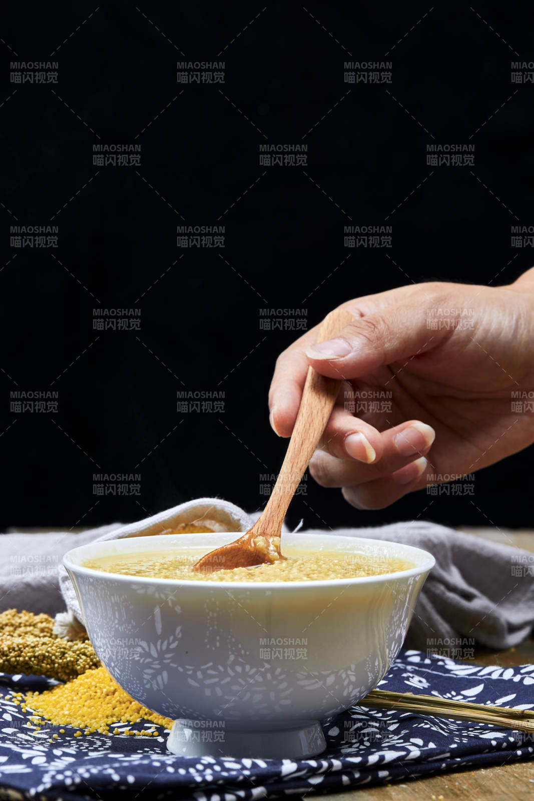 手持木勺㧟起的美味香浓小米粥图片