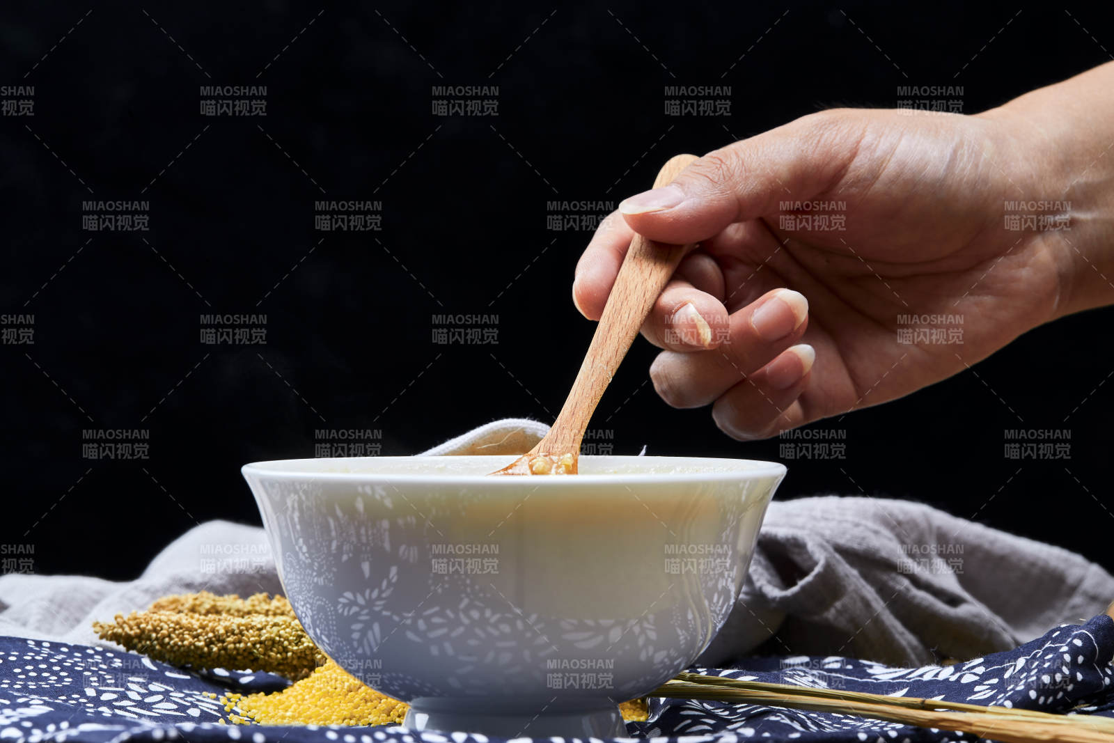 手持木勺㧟起的美味香浓小米粥图片