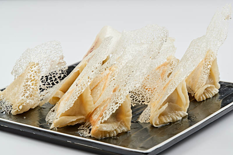 黑色瓷盘装的渔网水煎包图片