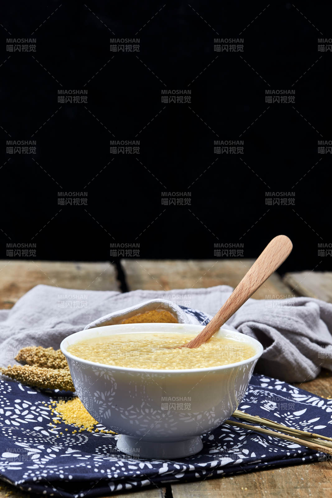手持木勺㧟起的美味香浓小米粥图片