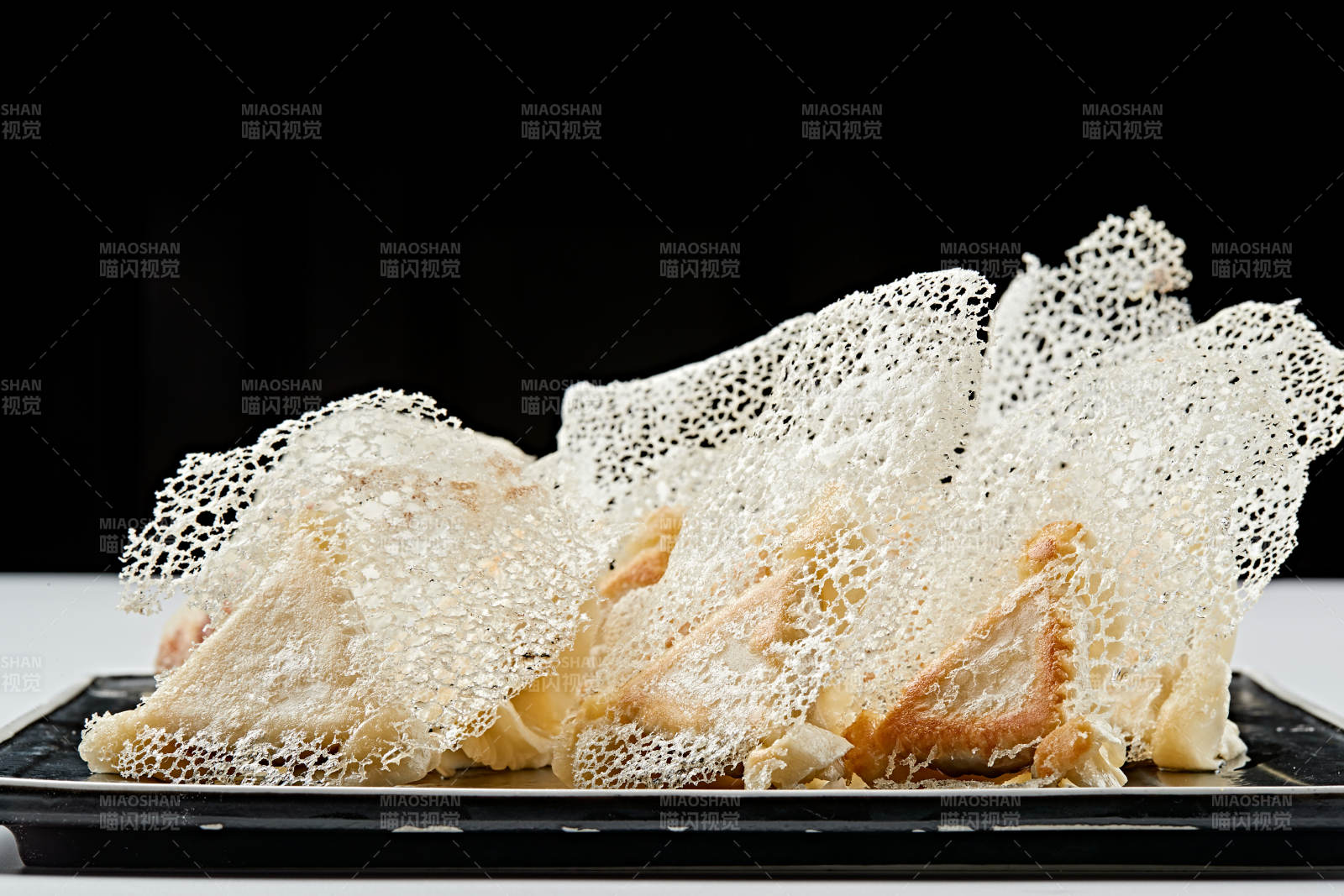 黑色瓷盘装的渔网水煎包图片