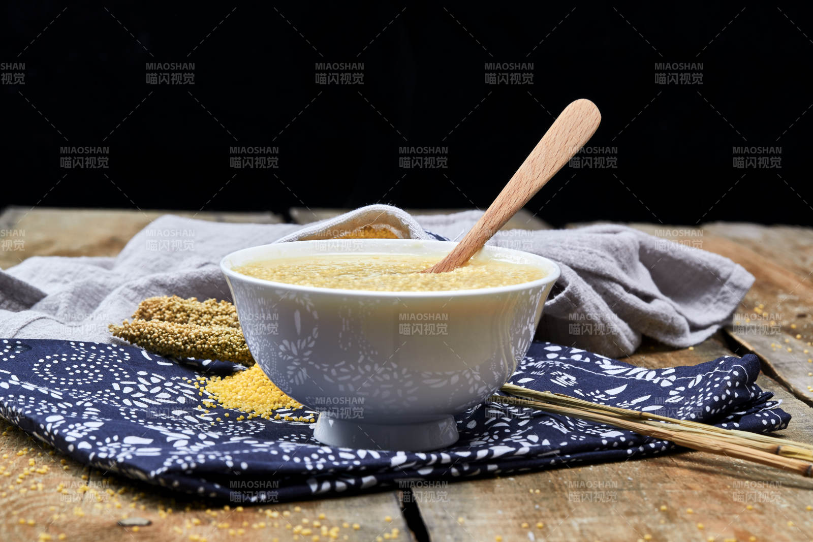 手持木勺㧟起的美味香浓小米粥图片
