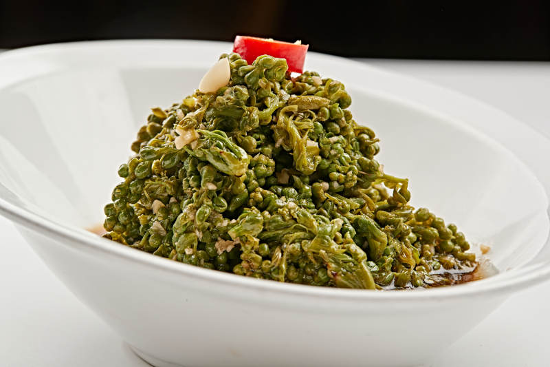 白色瓷盘装的醋腌凉拌木瓜花图片