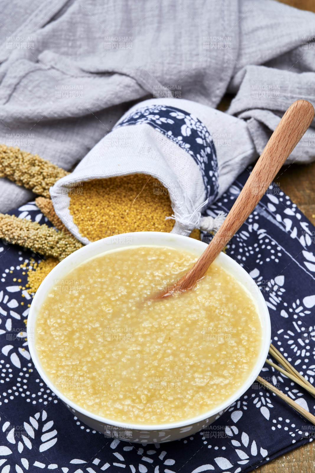手持木勺㧟起的美味香浓小米粥图片