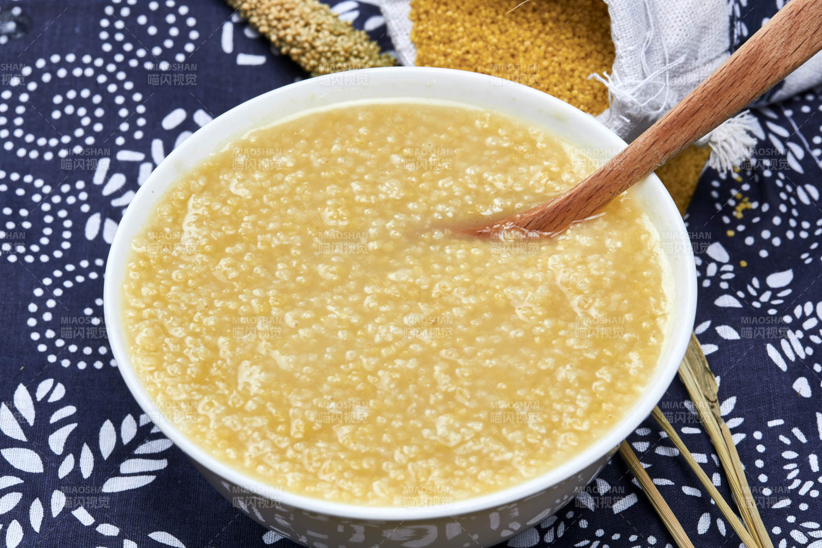 手持木勺㧟起的美味香浓小米粥图片