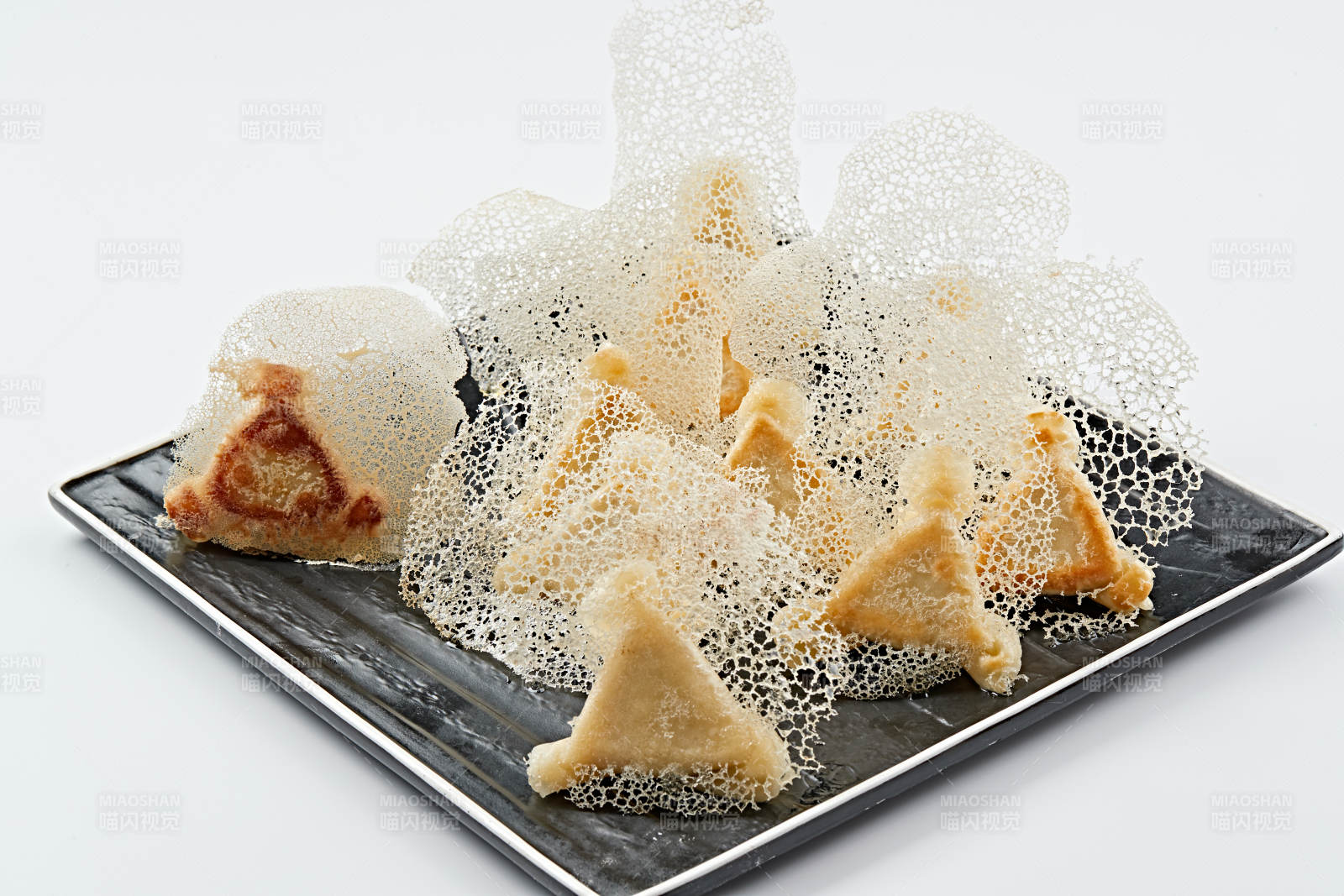 黑色瓷盘装的渔网水煎包图片